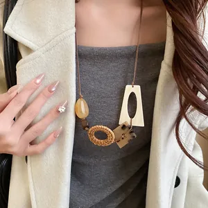 Close-up of bohemian woven wooden bead necklace styled on a model's white coat
