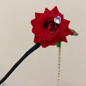 Macro view of a retro red rose hair stick featuring a crystal heart and pearl tassel.