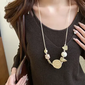 Detail of a bohemian rattan and wooden bead necklace on a model's brown sweater