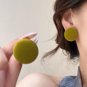 Detail view of olive green round fabric stud earrings featuring a retro matte texture