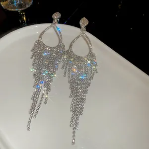 Close-up of sparkling long tassel earrings with shimmering rhinestones in silver finish