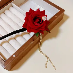 Detail view of a vintage red rose hair stick featuring a heart rhinestone and long tassel