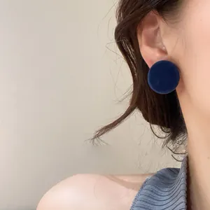 Close-up view of retro navy blue fabric round stud earrings worn on female ear for detail