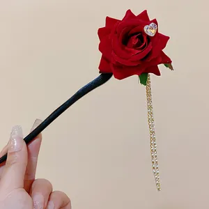 Macro view of vintage red rose hairpin with rhinestone heart and elegant long gold tassels