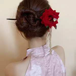 Detailed view of a vintage red rose hair stick with sparkling tassels worn in a bun
