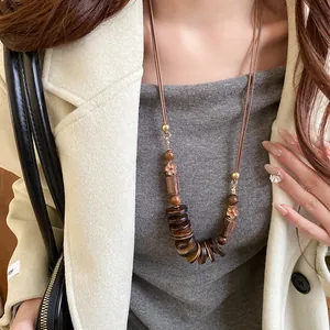 Detail shot of a bohemian long necklace featuring vintage wooden beads and flower charms.