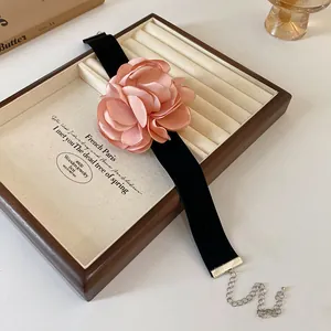 Vue détaillée d'une rose en tissu rose faite main sur un tour de cou en velours noir.