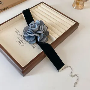 Vue détaillée d'un tour de cou rose en tissu gris sur un ruban de velours noir.