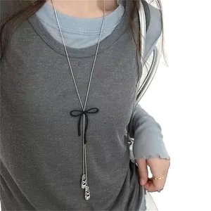 Elegant long sweater chain necklace featuring a black ribbon bow and silver ballet shoe pendants