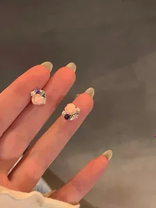 Gros plan de boucles d'oreilles fleurs avec détails en zircon et perle sur doigts.