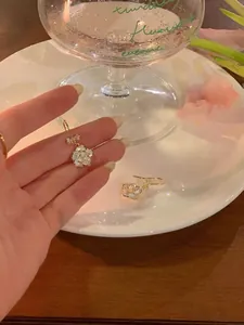 Détail de boucles d'oreilles fleurs dorées élégantes avec un lustre perlé dans la main
