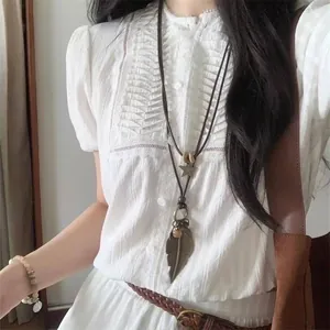 Close-up view of a vintage feather and star pendant necklace worn on a white blouse