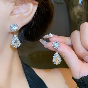 Detail shot of elegant sparkling waterdrop rhinestone earrings worn by an Asian model