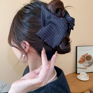 Vue rapprochée d'une pince à cheveux en tissu à pois noirs dans un chignon marron