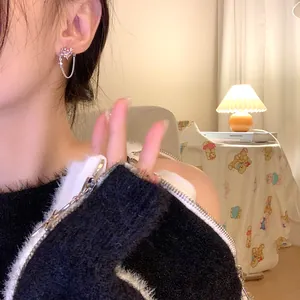 Gros plan d'une boucle d'oreille fleur dorée avec chaîne et zircone étincelante.