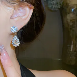 Detailed view of elegant silver-tone water drop rhinestone earrings worn by a model