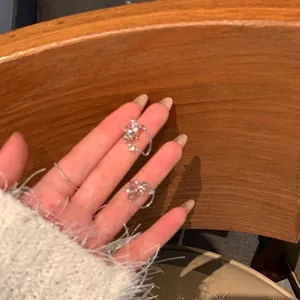 Gros plan de boucles d'oreilles fleur en zircon étincelant sur les doigts, lumière chaude