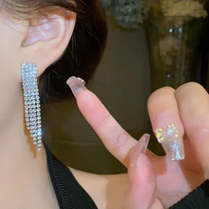 Close-up of sparkling rhinestone tassel earrings worn on ear for elegant style