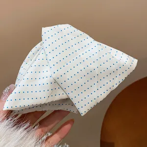 Gros plan d'une pince à cheveux en tissu blanc à pois bleus montrant des détails de texture