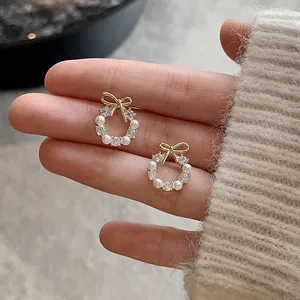 Vue détaillée de boucles d'oreilles couronne dorées avec perles et zircons fins