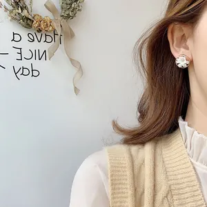 Gros plan montrant l'effet d'élégantes boucles d'oreilles fleurs en perles sur l'oreille