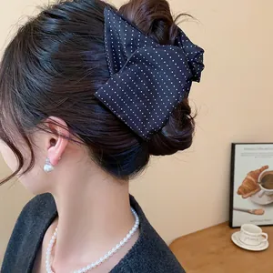 Gros plan d'une pince à cheveux élégante avec un nœud à pois noirs dans un chignon sophistiqué