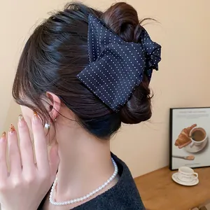 Vue détaillée d'une pince à cheveux à nœud noir à pois dans un élégant chignon coréen.