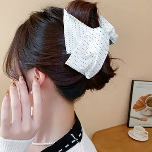 Gros plan d'une pince à cheveux à pois blancs avec nœud portée sur un chignon