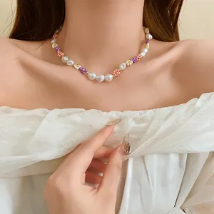 Close-up of a colorful beaded flower and pearl necklace on a female model's neck