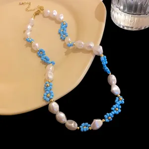 Close-up detail of a handmade blue bead flower and elegant white baroque pearl necklace