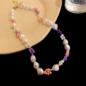 Detail view of a handcrafted necklace featuring irregular pearls and colorful seed bead flowers