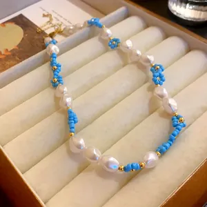 Close-up detail view of beaded blue flower and white baroque pearl necklace jewelry