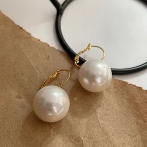 Elegant 14K gold plated round pearl hoop earrings on minimalist vintage background.