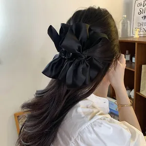 Detailweergave van een elegante oversized zwarte satijnen strik haarklem op het hoofd