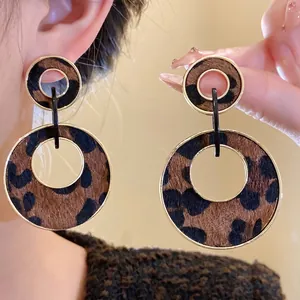 Stylish retro leopard print wood circular earrings with gold metal frames on model