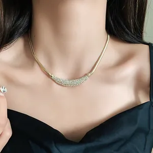 Close-up of elegant gold crescent necklace with pavé rhinestones on a snake chain