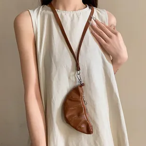 Monedero con forma de croissant en cuero sintético marrón usado como collar de moda con un top