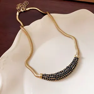 Close-up of golden snake chain necklace with black rhinestone crescent pendant