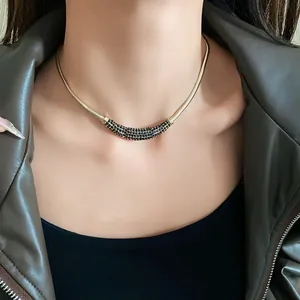 Detail view of a gold moon-shaped necklace with black stones worn with a leather jacket