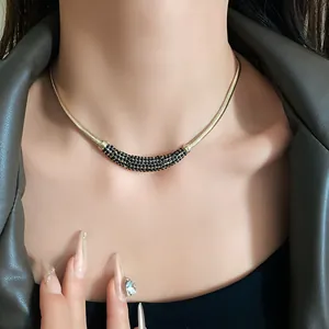 Close-up of elegant crescent necklace with black rhinestones on a gold snake chain