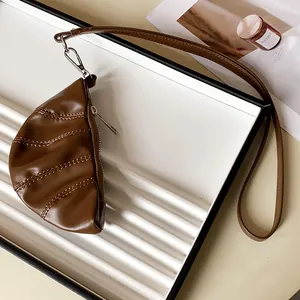 Detalle de un collar con forma de bolso croissant en cuero sintético marrón vintage