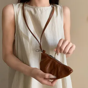 Detalle de un minibolso de collar con forma de croissant en cuero sintético vintage.