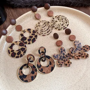 Detailed collection of vintage leopard print and wooden stud earrings on a ceramic plate