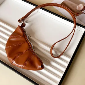 Detalle de un mini monedero con forma de cruasán en cuero sintético marrón de estilo retro