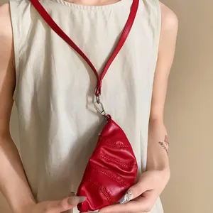 Detalle de un collar monedero de cuero sintético rojo con forma de cuerno vintage