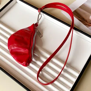 Vista detallada de un elegante collar monedero con forma de croissant en cuero rojo.
