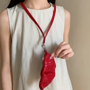 Modelo que lleva un collar monedero de croissant en cuero sintético rojo sobre top blanco