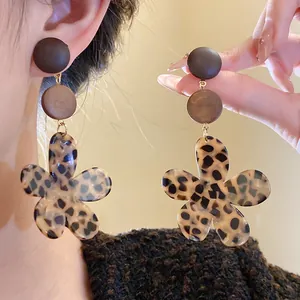 Close-up detail of vintage leopard print flower earrings with dark wooden disc studs