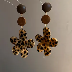 Detailed close-up showing retro leopard print flower earrings with wooden discs