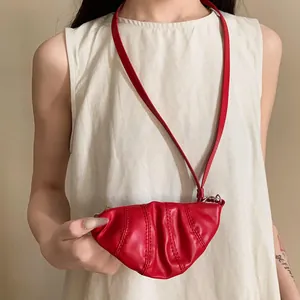 Vista detallada de un mini collar monedero rojo en forma de cruasán de cuero sintético